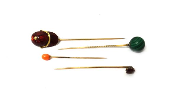 A gold and red enamelled stick pin, designed as a jockey's cap, a gold stick pin, with a malachite bead finial, a coral stick pin and a garnet set sti