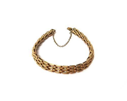 A gold bracelet, in a curved bar and oval link design, on a snap clasp, detailed 15, fitted with a safety chain, weight 17.1 gms.