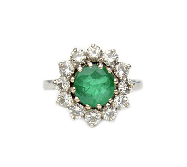 A white gold and platinum, emerald and diamond cluster ring, claw set with the circular cut emerald at the centre, in a surround of circular cut diamo