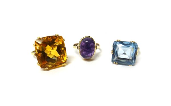 A gold ring, claw set with a large curved square cut citrine, a 9ct gold ring, mounted with an oval cabochon amethyst quartz and a 9ct gold and pale b