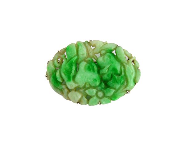 A carved jade oval brooch, the panel carved and pierced with two birds, a flower and fruit, with a case.   Illustrated