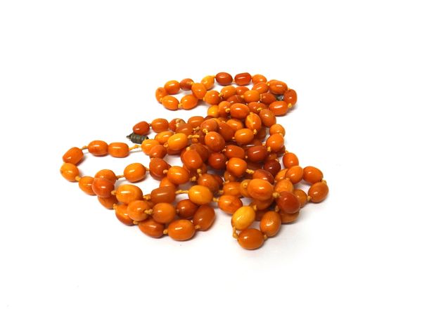 A single row necklace of oval vary coloured butterscotch coloured amber beads, length 134cm and a shorter single row necklace of oval vary coloured bu