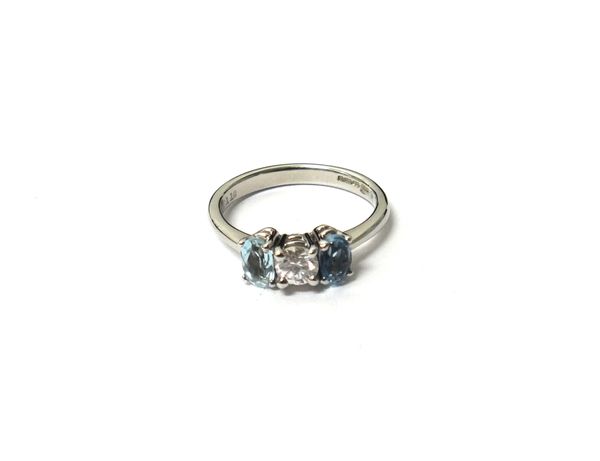 An 18ct  white gold, diamond and aquamarine set three stone ring, claw set with the circular cut diamond at the centre, between two oval cut aquamarin