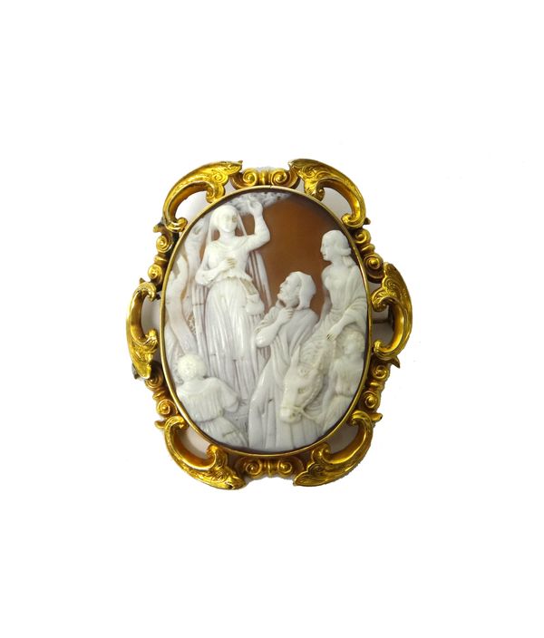 A Victorian gold mounted oval shell cameo brooch, carved as The Flight into Egypt, the mount decorated with a scrolling border and with engraved decor