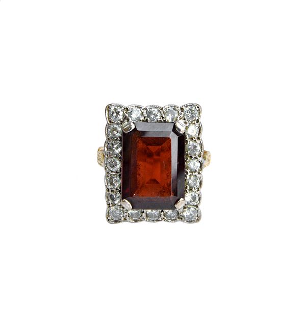 A gold, garnet and diamond set rectangular cluster ring, claw set with the cut cornered rectangular cut garnet at the centre, within a surround of cir