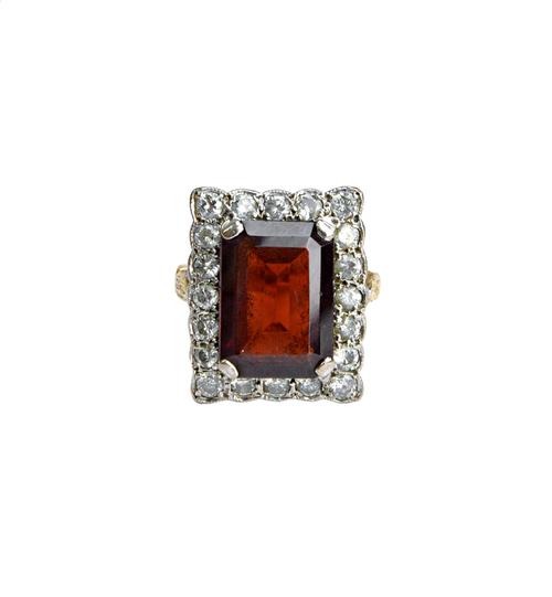 A gold, garnet and diamond set rectangular cluster ring, claw set with the cut cornered rectangular cut garnet at the centre, within a surround of cir
