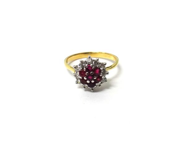 A gold, ruby and diamond set nineteen stone cluster ring, claw set with seven circular cut rubies at the centre, in a surround of twelve circular cut