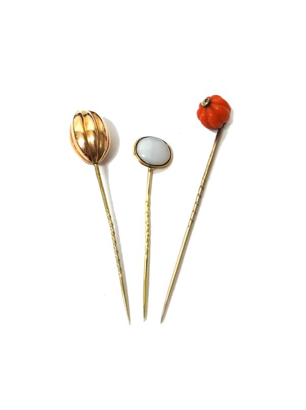 A gold stick pin, with a melon fluted coral bead terminal, a gold stick pin, with a fluted oval terminal and another stick pin, combined gross weight