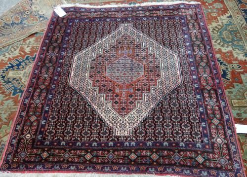 A Senneh rug, Persian, the black field with a bold madder and ivory medallion, all with a fine rosette design, a madder diamond and bracket border, 14