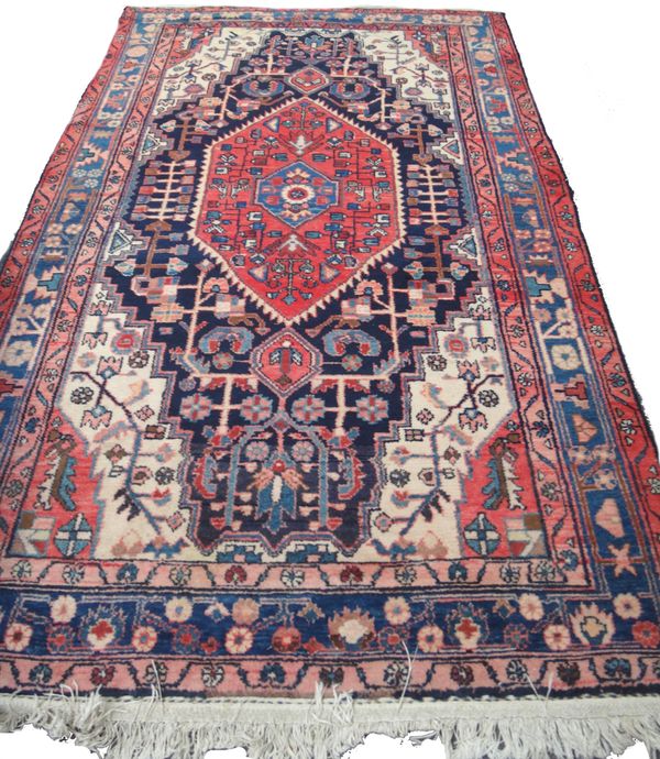 A Hamadan rug, Persian, the indigo field with a bold madder medallion, ivory spandrels, angular vines and an indigo floral border, 255cm x 148cm,