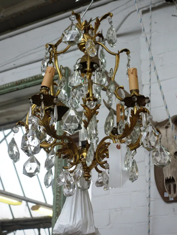 A French gilt metal and glass lustre four branch chandelier, 20th century, of open frame form, with a central glass obelisk, 55cm high.