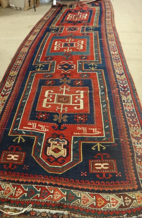 A Kazak runner, Caucasian, the dark indigo field with three bold connecting squares, an arrow border, dated 1335, 468cm x 160cm.