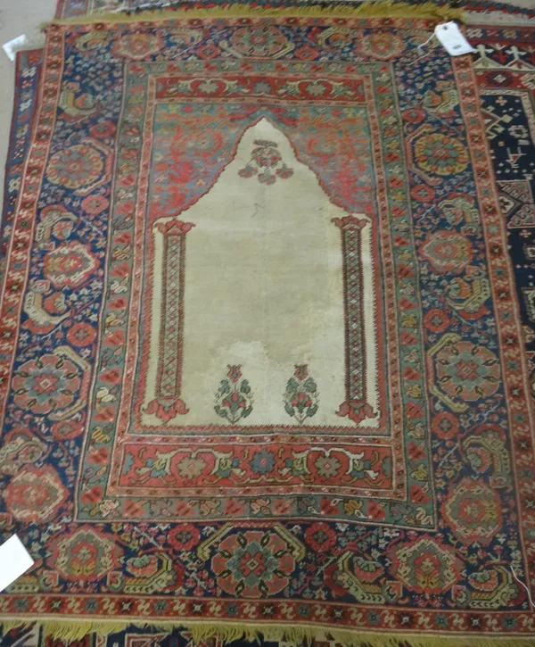 A Ghirordes prayer rug, the plain ivory mehrab with two pillars rising to an indigo arch, an indigo rosette and floral spray border, 136cm x 104cm.