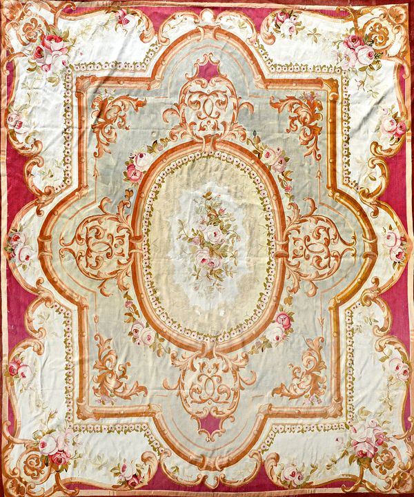 An Aubusson tapestry carpet, the central oval with a rose bouquet, shaped surrounds, ivory outer section with bouquets to corners, 386cm x 334cm.  Ill