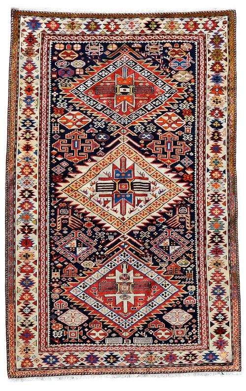 A Shirvan rug, Caucasian, the black field with an ivory and two madder stepped diamonds, all with birds, minor motifs, a pair of peacocks and other pa