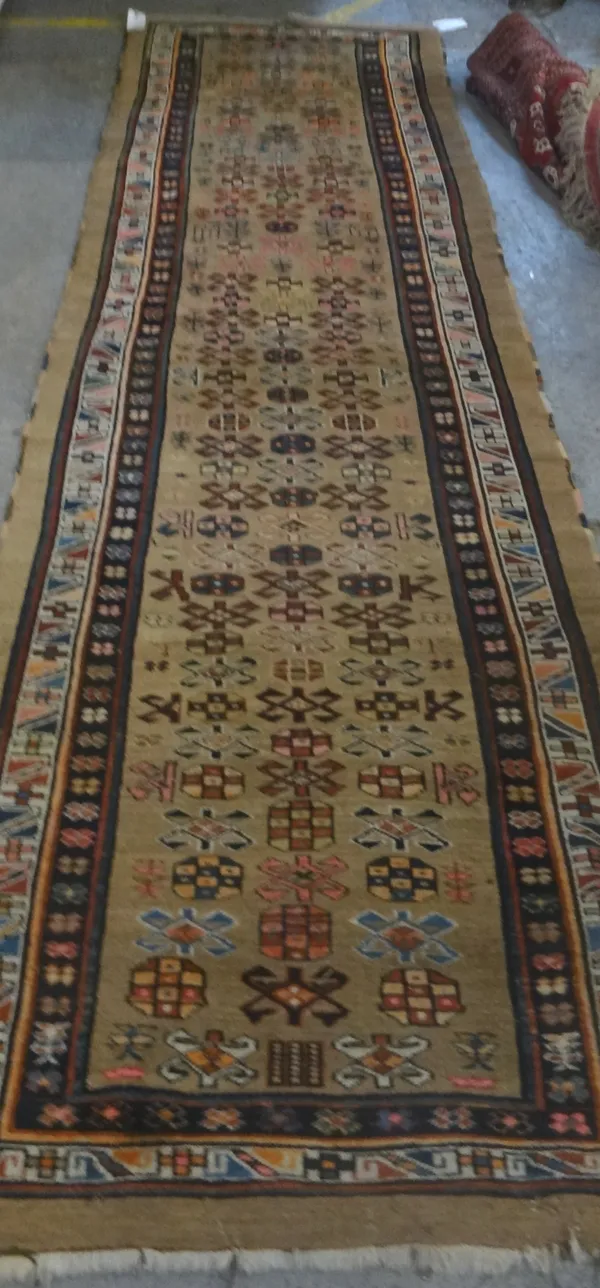 A North West Persian runner, the fawn field with rows of hooked motifs, single plants, birds and deer, an ivory flower and band border, 363cm x 106cm.