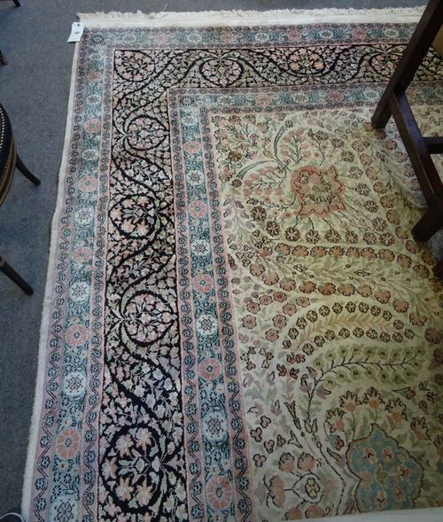 A large Indian carpet, the ivory field with central small medallion and foliate tendrils, black foliate main border and  guard bands, 360cm x 546cm.