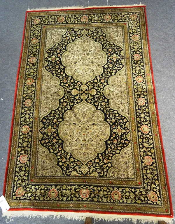 An Indian part silk rug, the black ground with two lozenge shaped medallions and a shaped spandrel border, with matching main border, 137cm x 209cm.