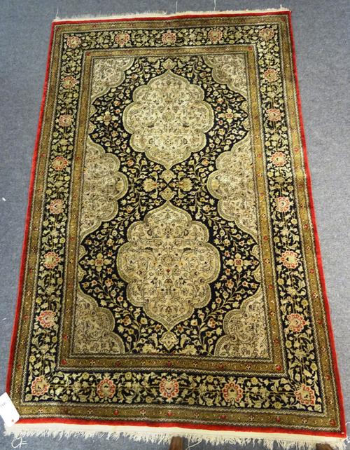 An Indian part silk rug, the black ground with two lozenge shaped medallions and a shaped spandrel border, with matching main border, 137cm x 209cm.