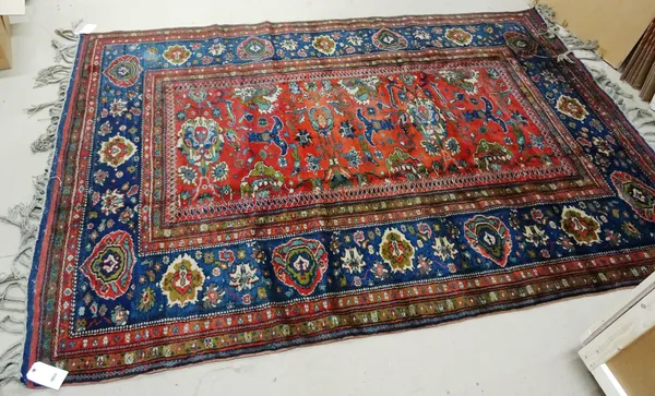 An Anatolian carpet, second half 20th century, the small red field with palmette motif and wide blue palmette border, a plaited fringe, 205cm x 300cm