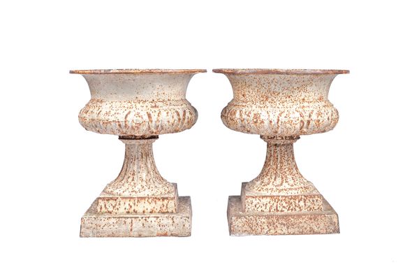 A pair of white painted cast iron jardinieres, each with semi lobed body and fluted socle, on square bases, 50cm wide x 57cm high, (2).  Illustrated