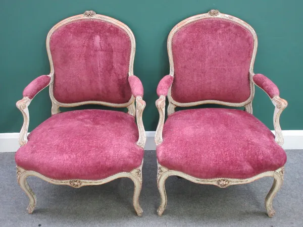 A pair of Louis XV style open armchairs, with serpentine seats and scroll supports, 70cm wide x 97cm high.
