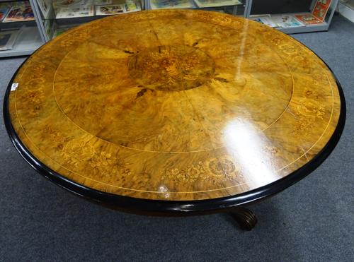 A mid Victorian breakfast table, the floral marquetry inlaid figured walnut circular snap top on hexagonal column and three carved downswept supports,