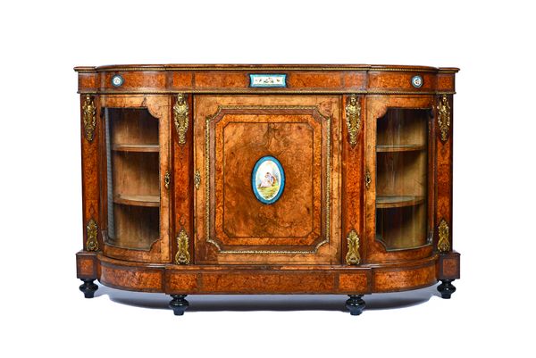 A Victorian gilt metal mounted figured walnut credenza, with ceramic mounted central panel door, flanked by glazed rounded doors, 183cm wide x 111cm h