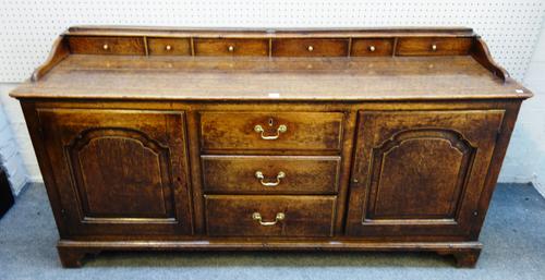 An 18th century oak dresser base, the plate rack with six spice drawers over three drawers flanked by cupboards, 170cm wide x 85cm high x 56cm deep.