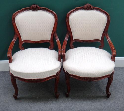 A pair of Louis XV style walnut framed open armchairs, each with bow seat and scroll supports, 55cm wide x 87cm high x 50cm deep. (2)