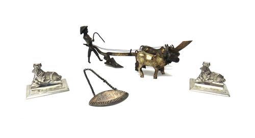 A pair of silver menu stands, each designed as a cat, with a handkerchief and with a bird cage on its side, with the door open, on a rectangular base,