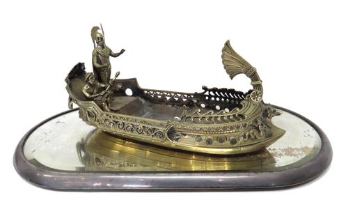 A Victorian formerly plated model of an ancient classical galley, with one standing and another seated classical figure, with ten detached oars and a
