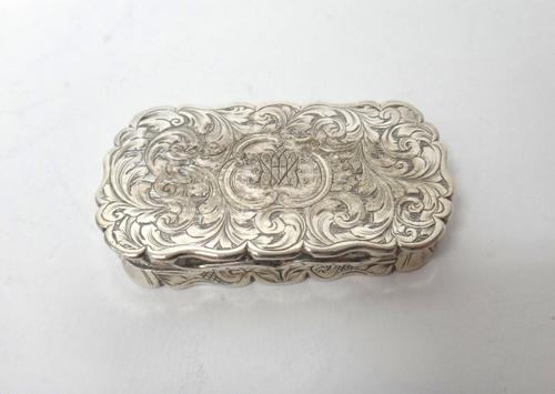 A Victorian silver vinaigrette, of curved rectangular form, gilt within with a scroll pierced and engraved grille, the exterior with feathered scroll