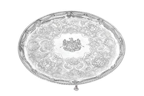 A Scottish silver large circular salver, the centre engraved with a coat of arms and a motto within a later engraved floral, foliate and scrolling bor