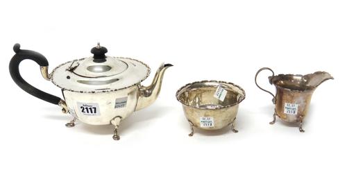 A silver three piece tea set, comprising; a teapot, a sugar bowl and a milk jug, each piece of shaped circular form and raised on three feet, the hall