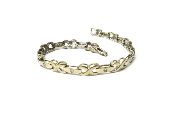 A white gold and diamond bracelet, in a twistover and tapered link design, mounted with circular cut diamonds at intervals, on a foldover clasp, detai