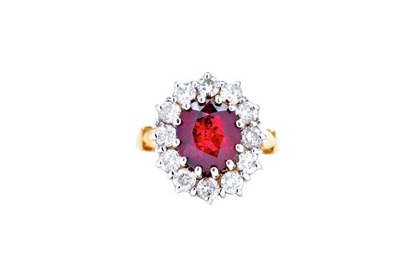 An 18ct gold, ruby and diamond oval cluster ring, claw set with the oval cut ruby at the centre, in a surround of twelve circular cut diamonds, ring s