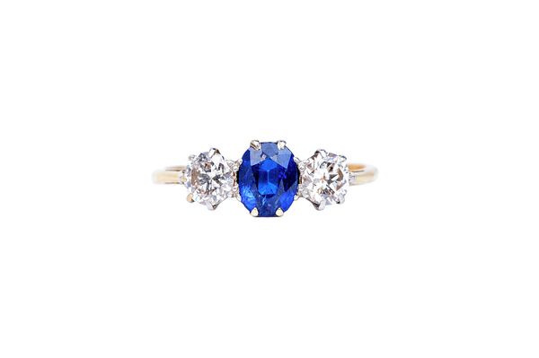 A gold, sapphire and diamond set three stone ring, claw set with an oval cut sapphire at the centre, between two circular cut diamonds, detailed 18 CT