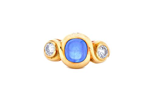 An 18ct gold, cabochon sapphire and diamond set three stone ring, by Annabel Jones, mounted with the cabochon sapphire between two circular cut diamon