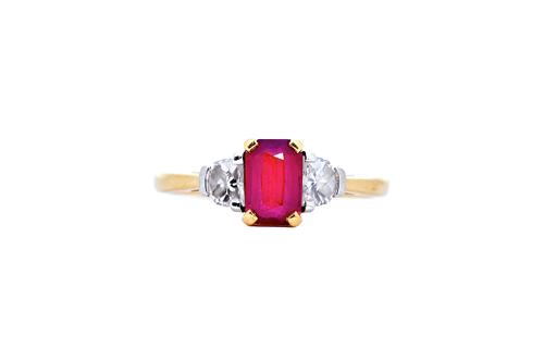 An 18ct gold, ruby and diamond three stone ring, claw set with a central cushion cut ruby, weight approx. 1.1cts, between two half moon shaped diamond