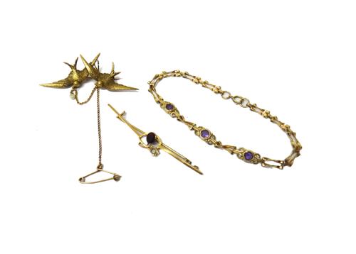 A gold and seed pearl brooch, designed as two swallows in flight, detailed 15 CT, fitted with a safety chain, with a case, a gold, amethyst and seed p