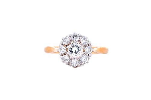 A gold and diamond nine stone cluster ring, claw set with circular cut diamonds and with the principal diamond mounted at the centre, detailed 18 CT,