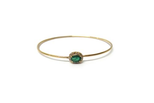 A gold, emerald and diamond set oval cluster bangle, of sprung form, claw set with the oval cut ruby at the centre, in a surround of circular cut diam