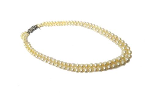 A two row necklace of graduated cultured pearls, on a white gold and diamond set pierced shaped rectangular clasp, mounted with the principal cushion