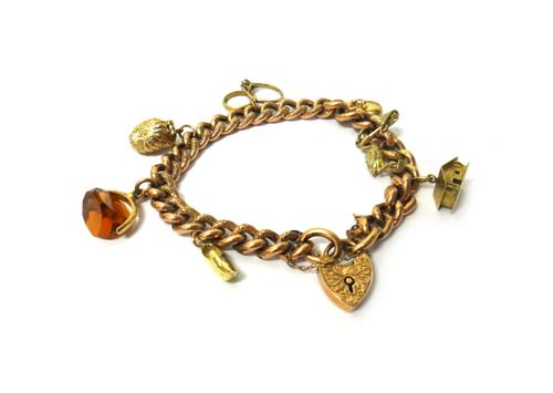 A gold decorated curb link bracelet, on an engraved heart shaped padlock clasp, detailed 9 C, fitted with seven pendants and charms, including a chale