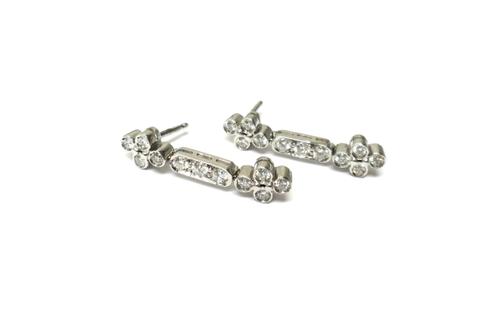 A pair of diamond set drop earrings, each mounted with a cluster of four circular cut diamonds at each end, connected by a central three stone diamond