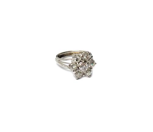A diamond set seven stone cluster ring, mounted with a cushion shaped diamond at the centre, in a surround of six larger cushion shaped diamonds, in a