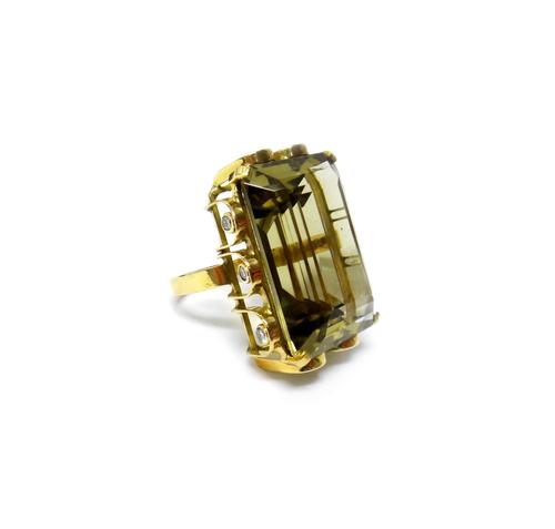 A gold ring, claw set with a large cut cornered rectangular step cut smoky quartz at the centre, within a pierced arcaded surround, collet set with te