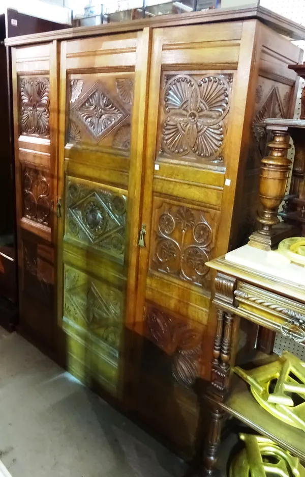 A 20th century oak triple wardrobe, the three doors each with three acanthus carved panels, the central section with internal drawers, 145cm 145cm wid