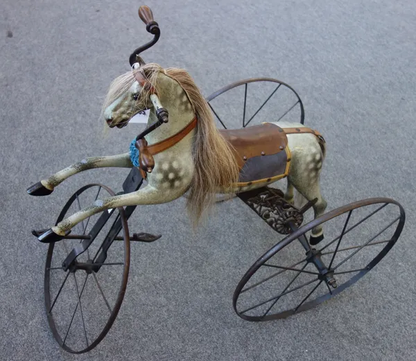 A Victorian and later child's velocipede 'horse' tricycle, dapple grey with leather saddlery, the rear wheels chain driven by rotating hand pedals, 76